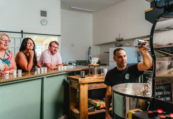 Elio roasting coffee as experience attendees view from the counter and sip on coffee