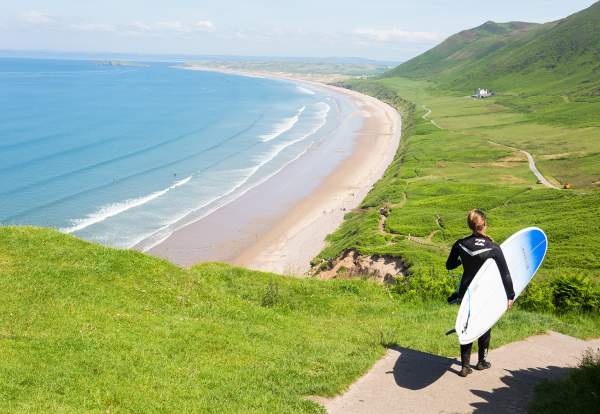 Surfer walking down to Rhossili Bay Beach