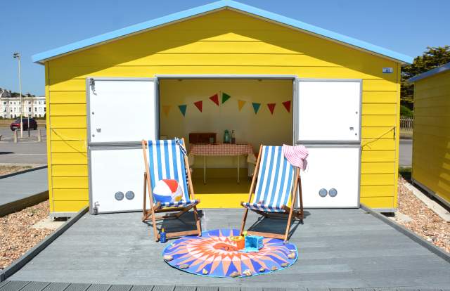Accessible Beach Hut Littlehampton - a yellow beach hut with double opening doors and a decking area accessed via a ramp.