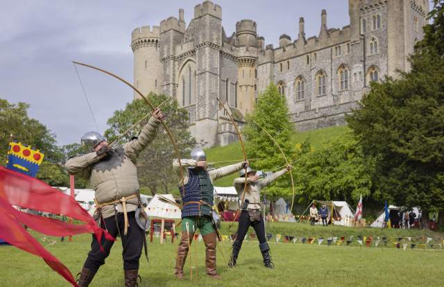 Three archers taking aim in medieval costume in the grounds of Arundel Castle in Sussex