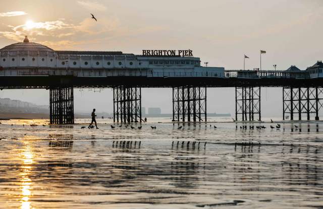Brighton pier at low tide with the sun rising in the background
