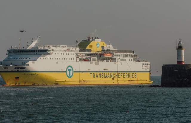 Yellow and white cross channel ferry coming in to port at Newhaven, with lighthouse in view