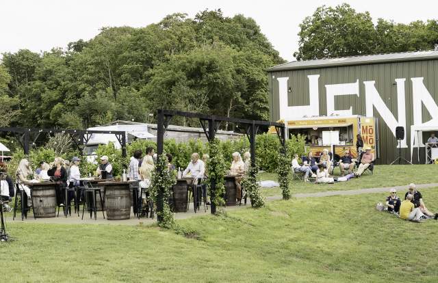 Henners vineyard with a large building in the background and people enjoying al fresco food and drink