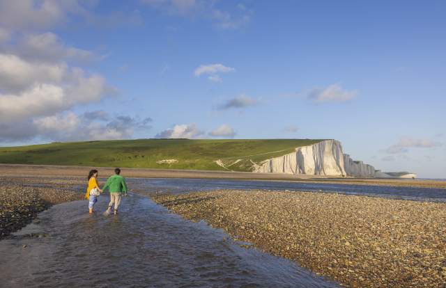 A couple walk in the water at low tide near Seven Sisters
