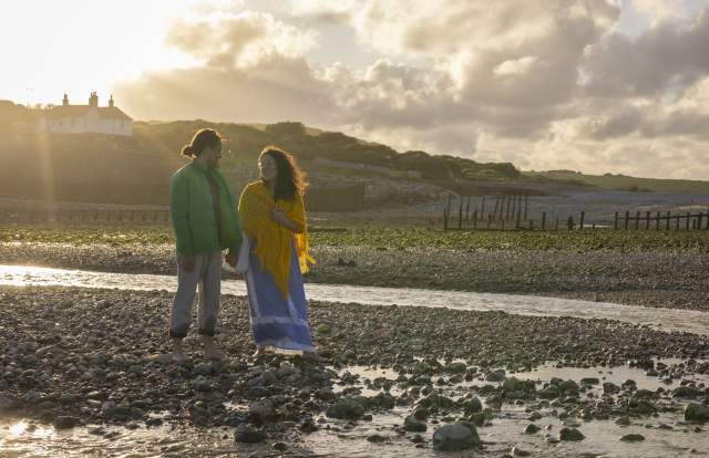 A couple stand on the rocky shore at Cuckmere Haven near Seaford Head, Sussex