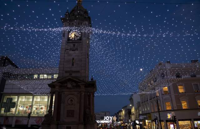 A clocktower lit with fairy lights in the middle of Brighton city centre, at night