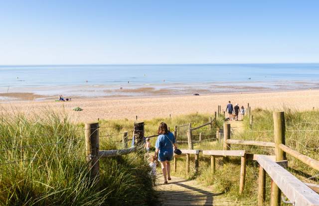 West Beach sand dunes and blue sea with people walking towards the sea on a wooden board walk