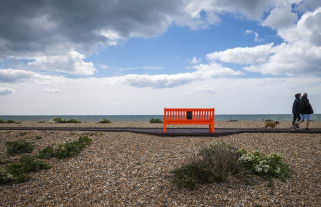 A shingle beach with red bench