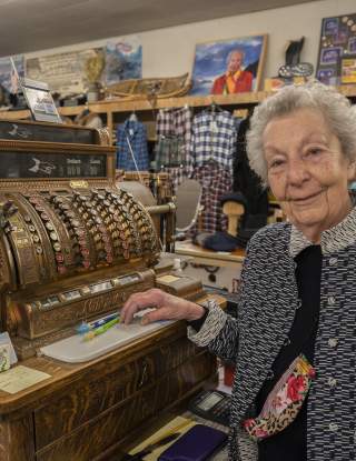 Dorothy Urbach smiling in front of vintage register