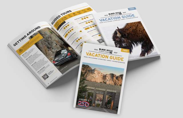 Black Hills & Badlands Vacation Guide with the summer cover, the winter cover, and opened to a page