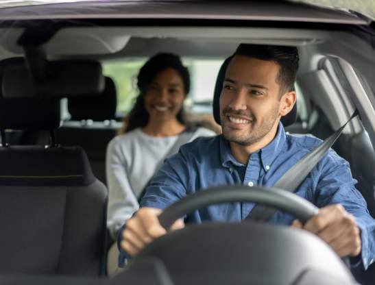 Latin American driver transporting a woman in a car while talking to her