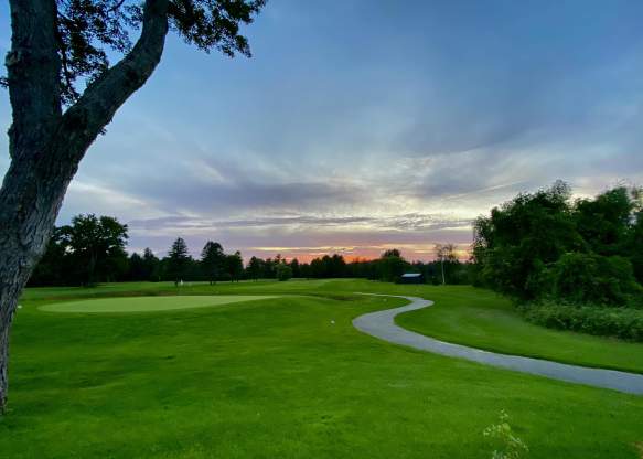 Picture of golf course, trees and a sunset