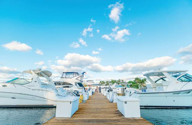 A couple walk a dock lined with boats near Nauti Dog in Lighthouse Point
