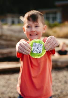 Child finding hidden glass medallion as part of Art of the Game glass art scavenger hunt.