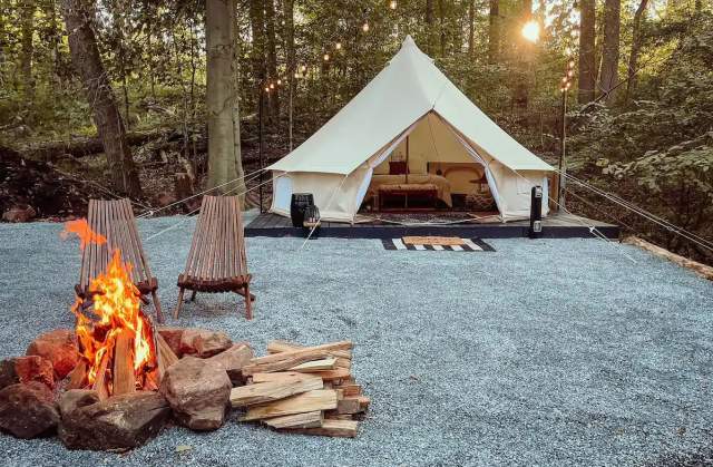 A glamping tent with a lit fire and chairs in front