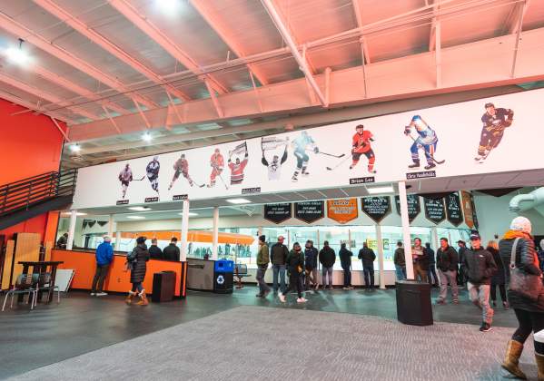crowd watching hockey from the lobby of a hockey arena