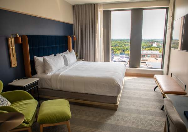 interior of hotel room with white sheets and a view of the city