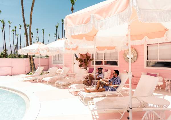 Two guys sitting in lounge chairs at the pink Trixie motel in Palm Springs