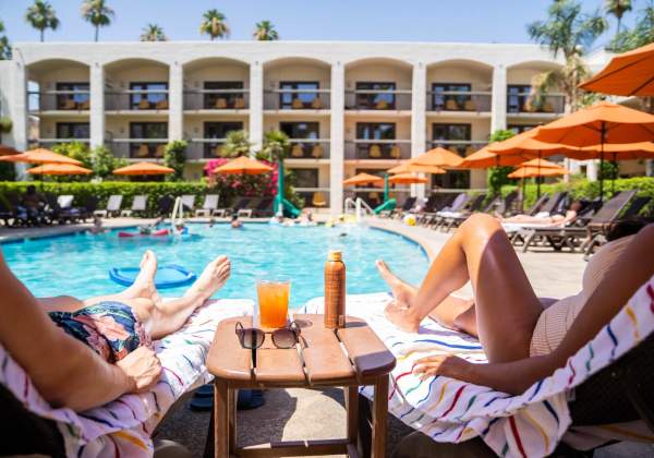 People sitting around a pool and swimming, on a sunny day