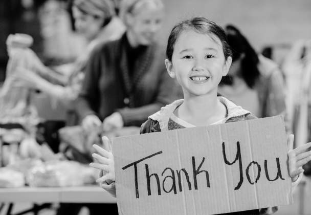 A child with a cardboard sign saying thank you