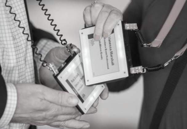 Two delegates holding electronic badges