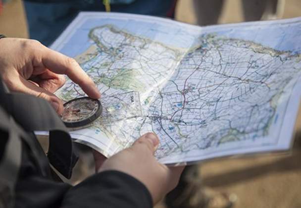 person holding a compass and a map