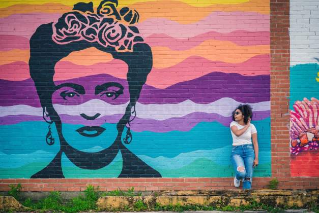Woman leaning on the wall next to the Frida Kahlo mural in downtown Beaumont