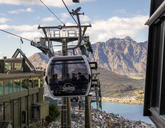People sitting inside the Skyline Gondola with views of Lake Whakatipu and the Remarkables Mountain