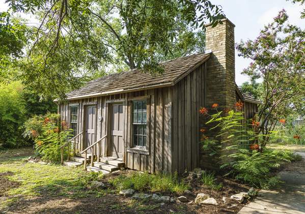Historic Haskell House with blooming flowers around the exterior