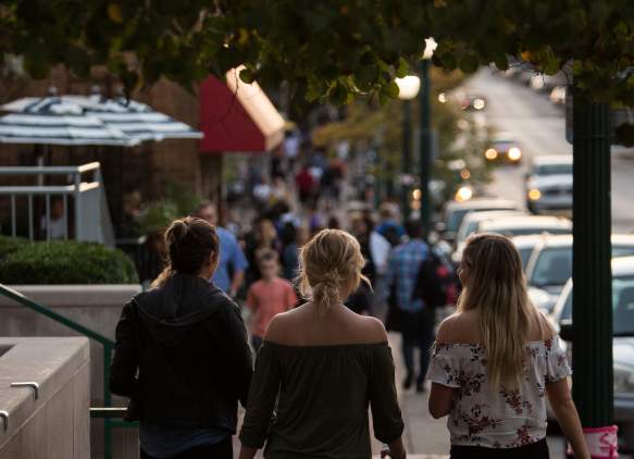 Three women walking down Kirkwood Avenue on a fall evening