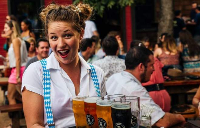 Woman wearing a white shirt and blue suspenders holding a platter of beer at Banger's Oktoberfest