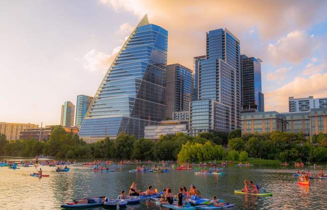 Image of people kayaking on Lady Bird Lake with the downtown skyline in the background.