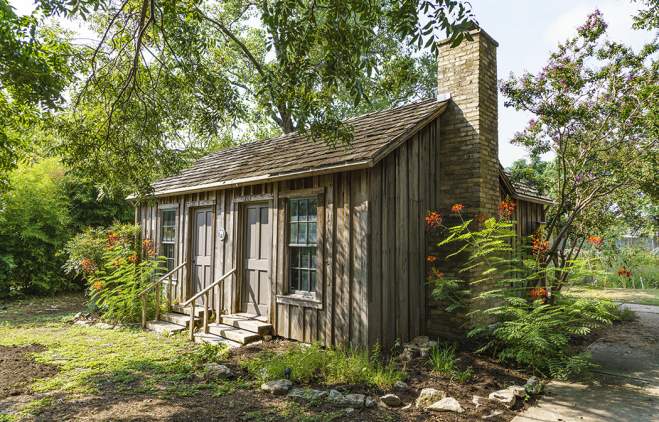Historic Haskell House with blooming flowers around the exterior