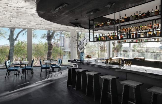 Monocrome bar with restaurant tables and floor to ceiling windows in the background.