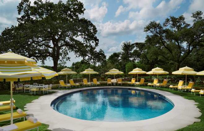 Commodore Perry Estate Pool surrounded by yellow chairs and umbrellas in Austin Texas