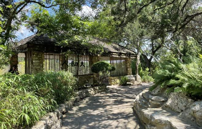 Shaded concrete pathway in the Taniguchi Japanese Garden at Zilker Botanical Garden.