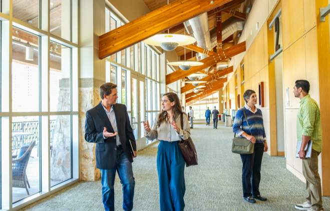 Men and women in professional attire gathering in pre-function space during a conference.