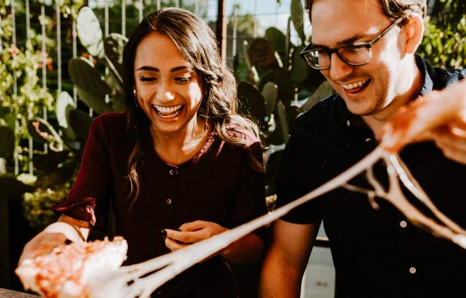 Couple pulling two pieces of cheesy pepperoni pizza apart from Via 313