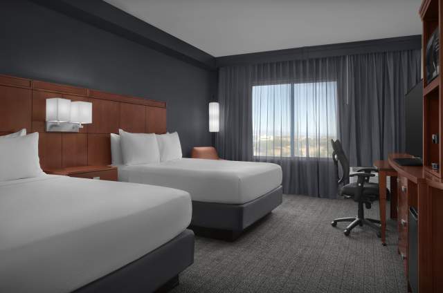 Courtyard by Marriott Phoenix Chandler/Fashion Center guest room with two queen beds, a desk with chair, and a dresser.