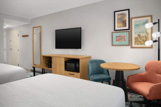Hampton Inn & Suites Phoenix Chandler-Fashion Center guest room with two queen beds, television, a table, and Arizona cactus photos on the wall.