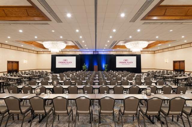 ballroom of the Crowne Plaza Phoenix Chandler Golf Resort set with tables, chairs and screens with overhead chandeliers