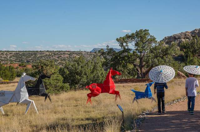 Boys walking past large metal origami horses
