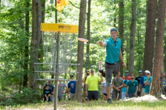 Pro disc golfer throwing disc into basket at PDGA International Disc Golf Center