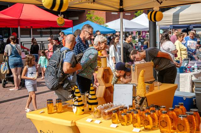 Patrons look over honey offerings at the Summit City Farmers Market at Electric Works in Fort Wayne