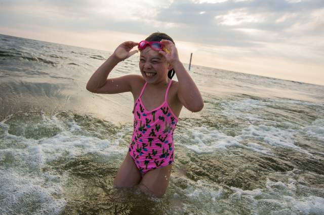 girl with pink bathing suit and goggles coming out of lake michigan