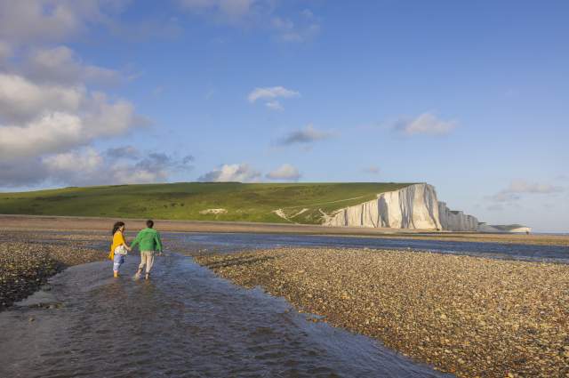A couple walk in the water at low tide near Seven Sisters