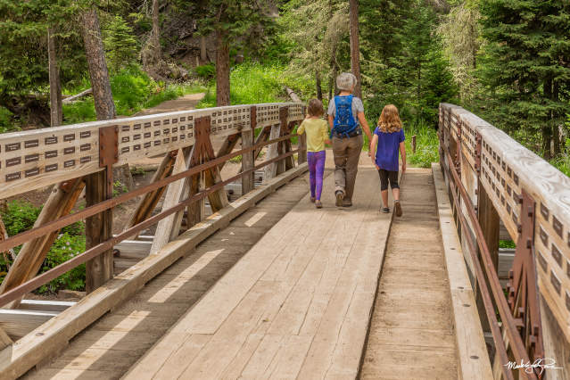 Group of 3 walking over the Ousel Falls Bridge