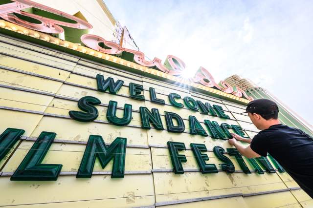 A man sets up letters on the Boulder Theater marquee that read "Welcome Sundance Film Festival"