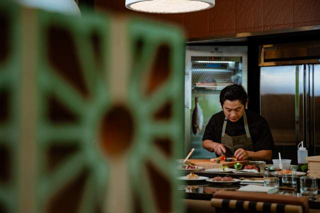 A sushi chef prepares dishes behind an out-of-focus wall at Wellness Counter in Boulder, CO
