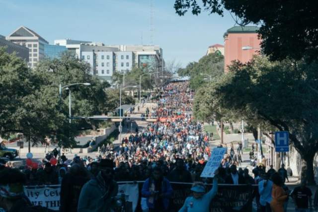 A large mass of people fills the street during a MLK Day march.